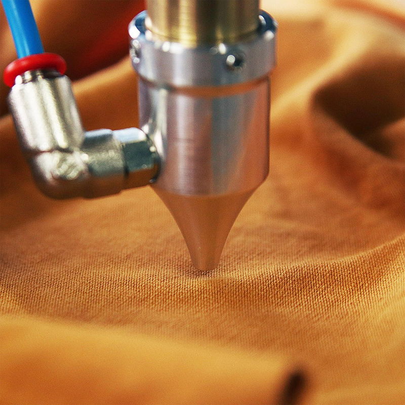 Close-up of a blue laser engraver machine working on a wooden surface, symbolizing custom craft.